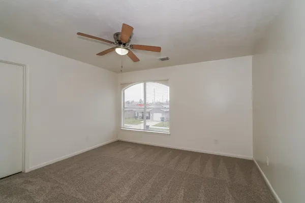an empty room with a window and a fan