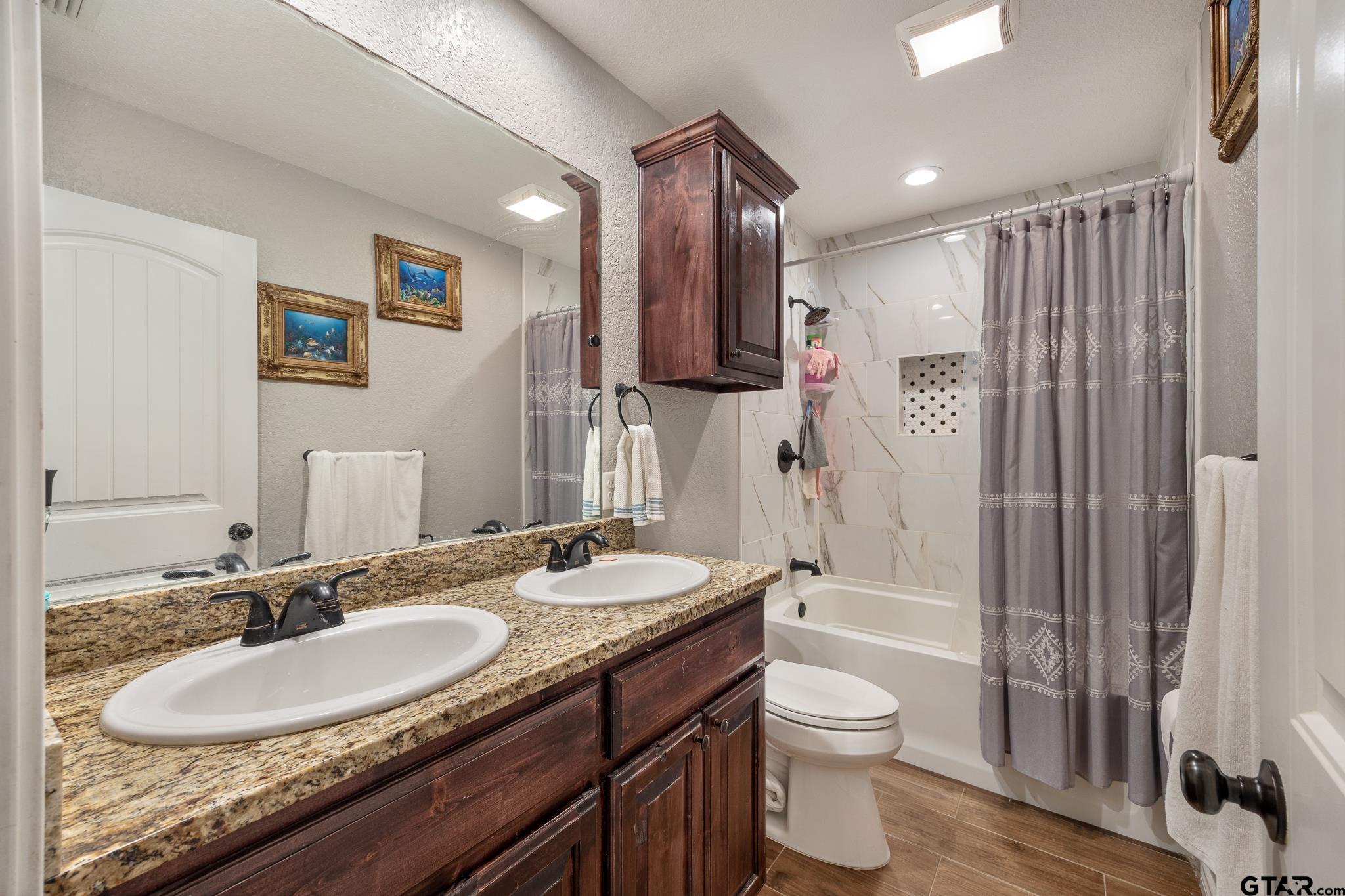 7573 County Road 48 Tyler, TX 75704 - Photo 20 of 31 a bathroom with a granite countertop sink toilet a mirror and shower