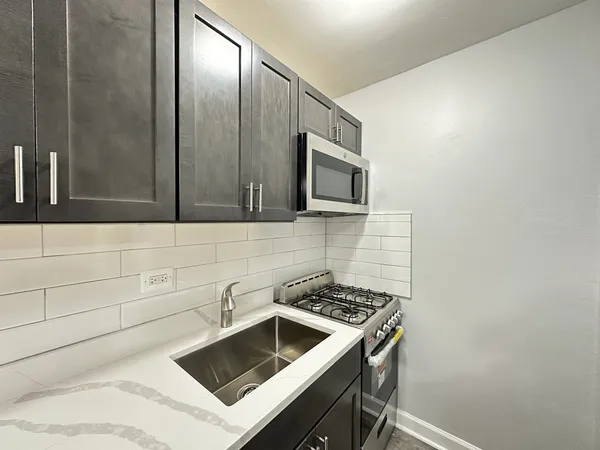 a kitchen with granite countertop a sink and a stove top oven with wooden floor