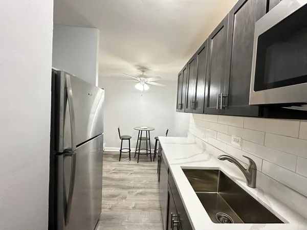 a kitchen with granite countertop stainless steel appliances a refrigerator microwave and stove top oven