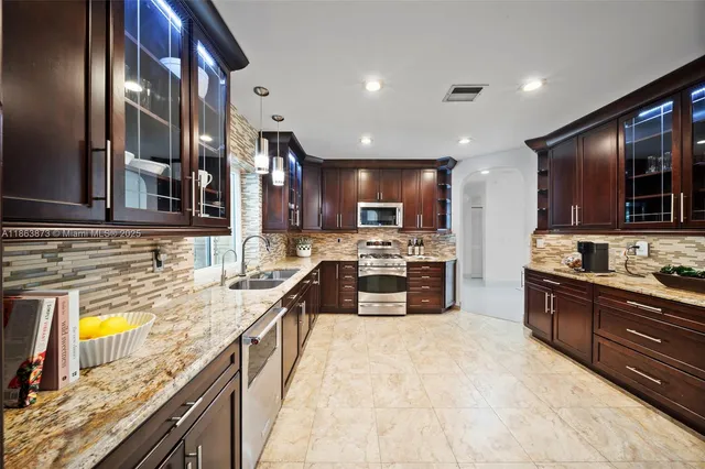 a kitchen with stainless steel appliances granite countertop a sink stove and refrigerator