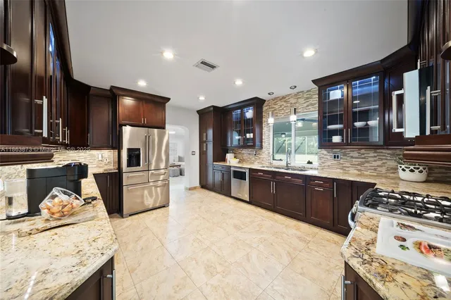 a kitchen with stainless steel appliances kitchen island granite countertop a stove refrigerator and cabinets