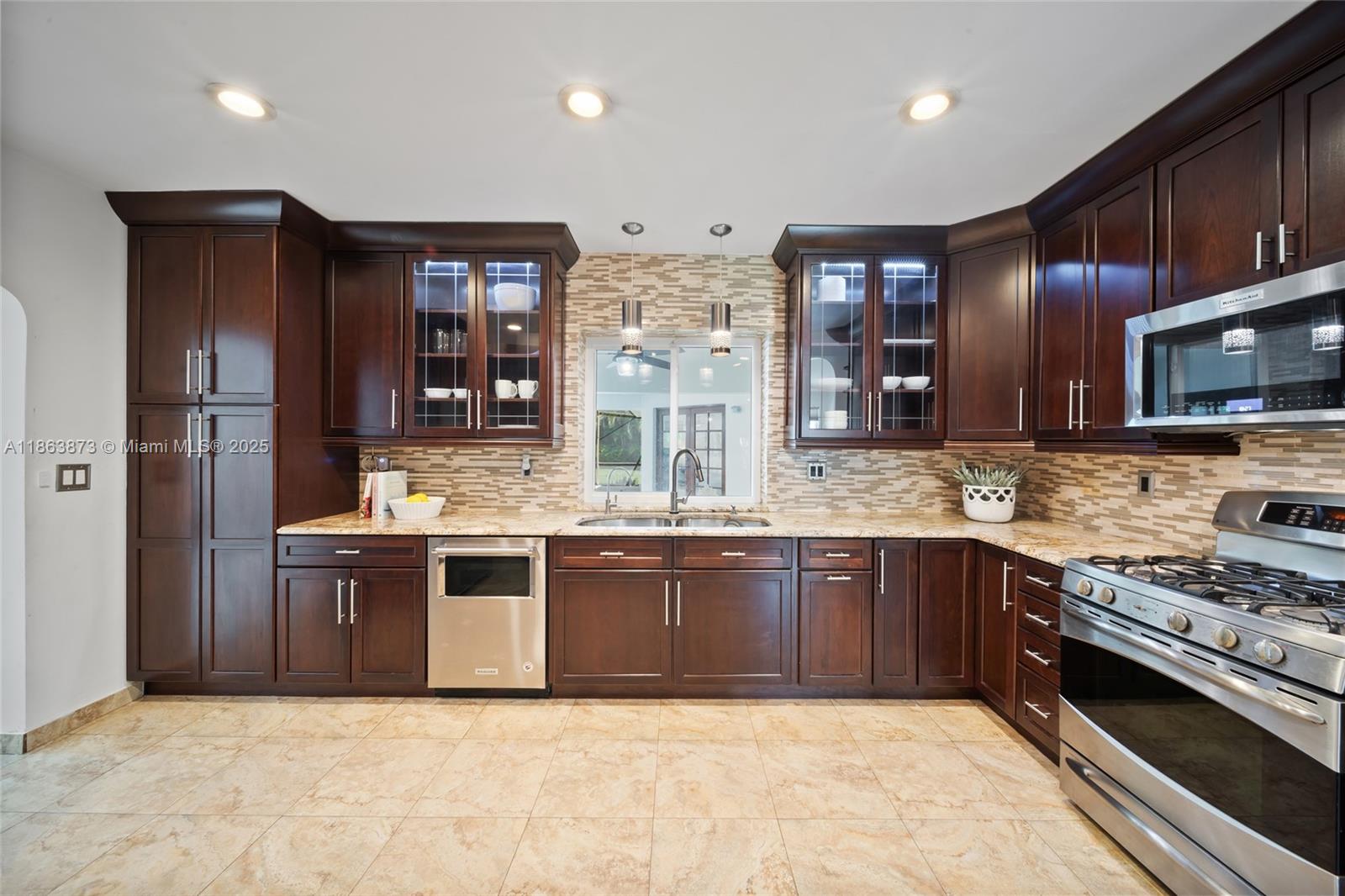 6125 Southwest 109th Street Pinecrest, FL 33156 - Photo 19 of 40 a large kitchen with stainless steel appliances granite countertop a stove and a sink