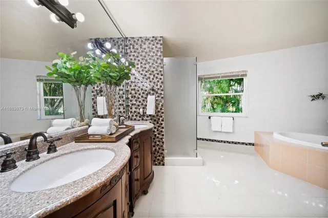 a bathroom with a granite countertop sink a mirror and a bathtub