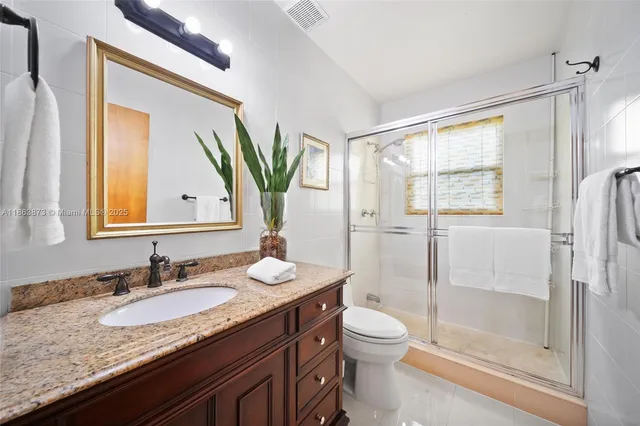 a bathroom with a granite countertop sink toilet and shower