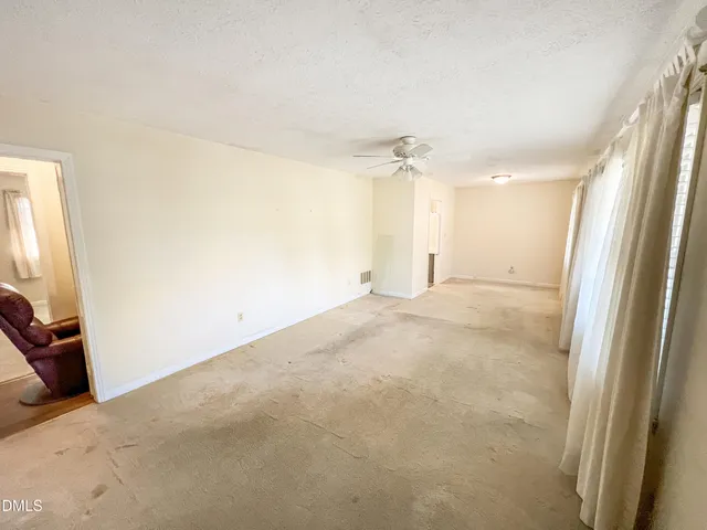 an empty room with windows and fan