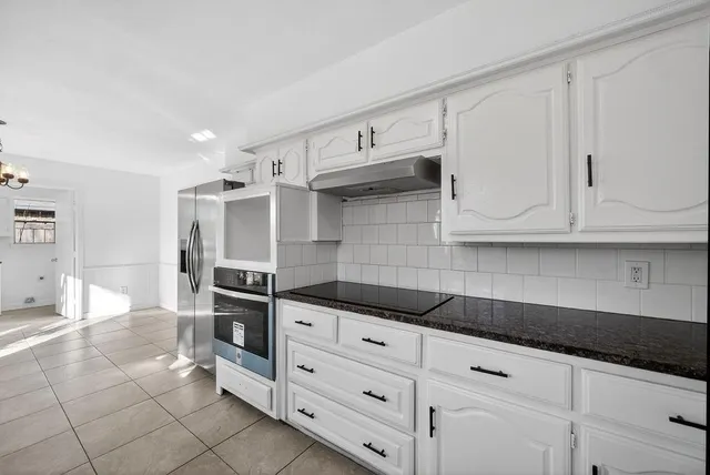 a kitchen with granite countertop white cabinets and stainless steel appliances