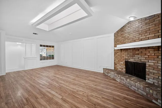 a view of empty room with wooden floor and fireplace