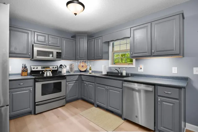 a kitchen with granite countertop cabinets stainless steel appliances and a window