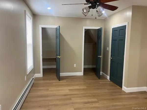 an empty room with wooden floor cabinet and a ceiling fan