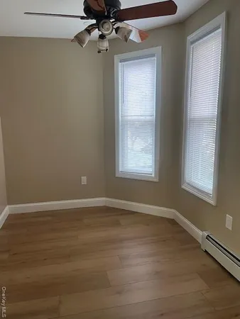 an empty room with wooden floor fan and windows