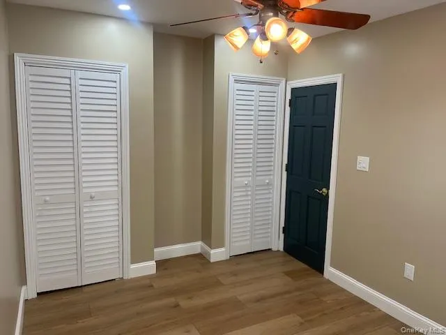 an empty room with wooden floor closet and windows