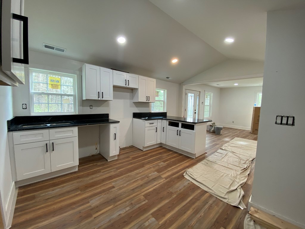 183 Hardy Street Resaca, GA 30735 - Photo 9 of 29 a large white kitchen with kitchen island a sink dishwasher a stove and a refrigerator with wooden floor