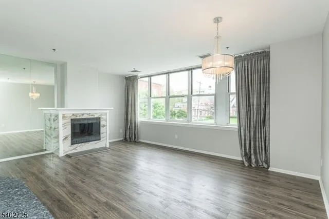 an empty room with wooden floor fireplace and windows