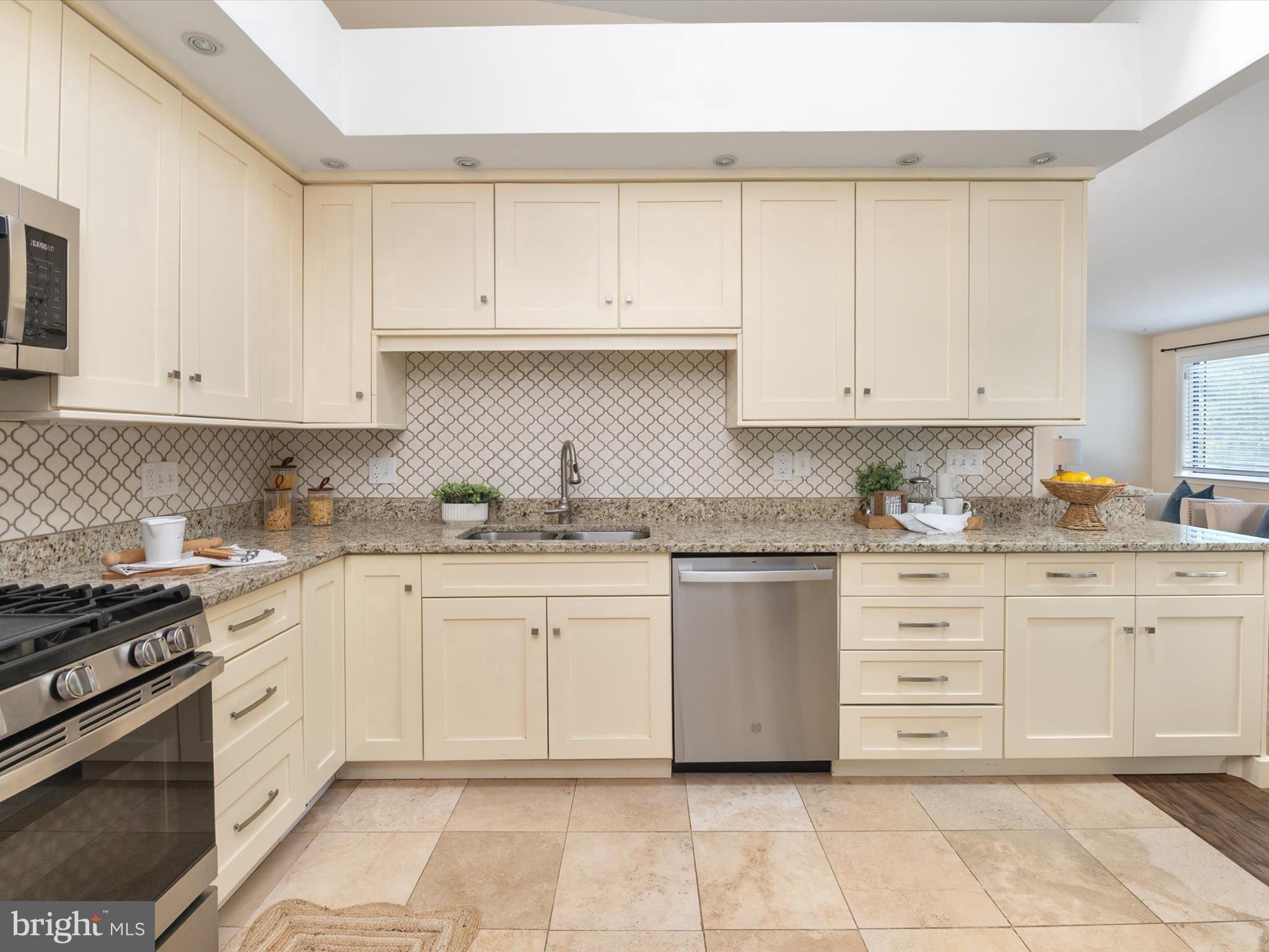 a kitchen with granite countertop white cabinets and stainless steel appliances