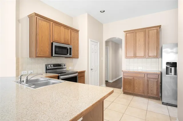 a kitchen with granite countertop a refrigerator stove top oven and sink
