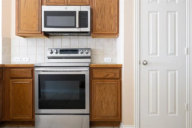 a kitchen with stainless steel appliances granite countertop white cabinets and a stove top oven