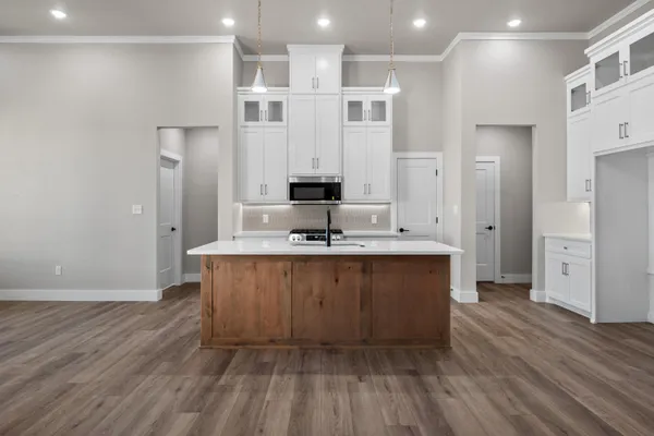 a kitchen with kitchen island granite countertop a sink cabinets and wooden floor