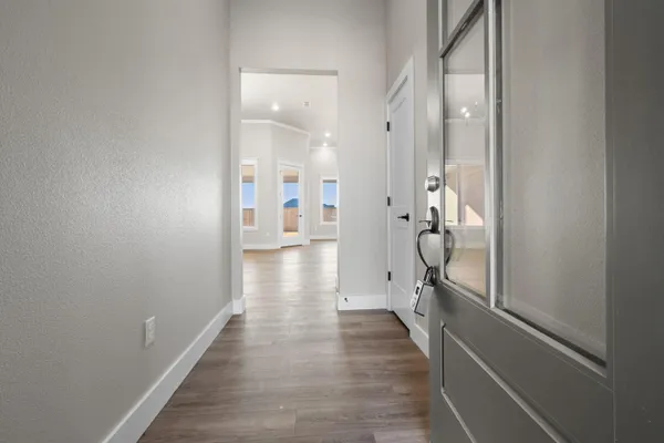 a view of a hallway with wooden floor and a bathroom