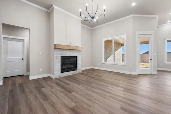 a view of an empty room with wooden floor fireplace and a window