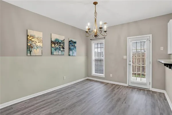 an empty room with wooden floor chandelier and windows