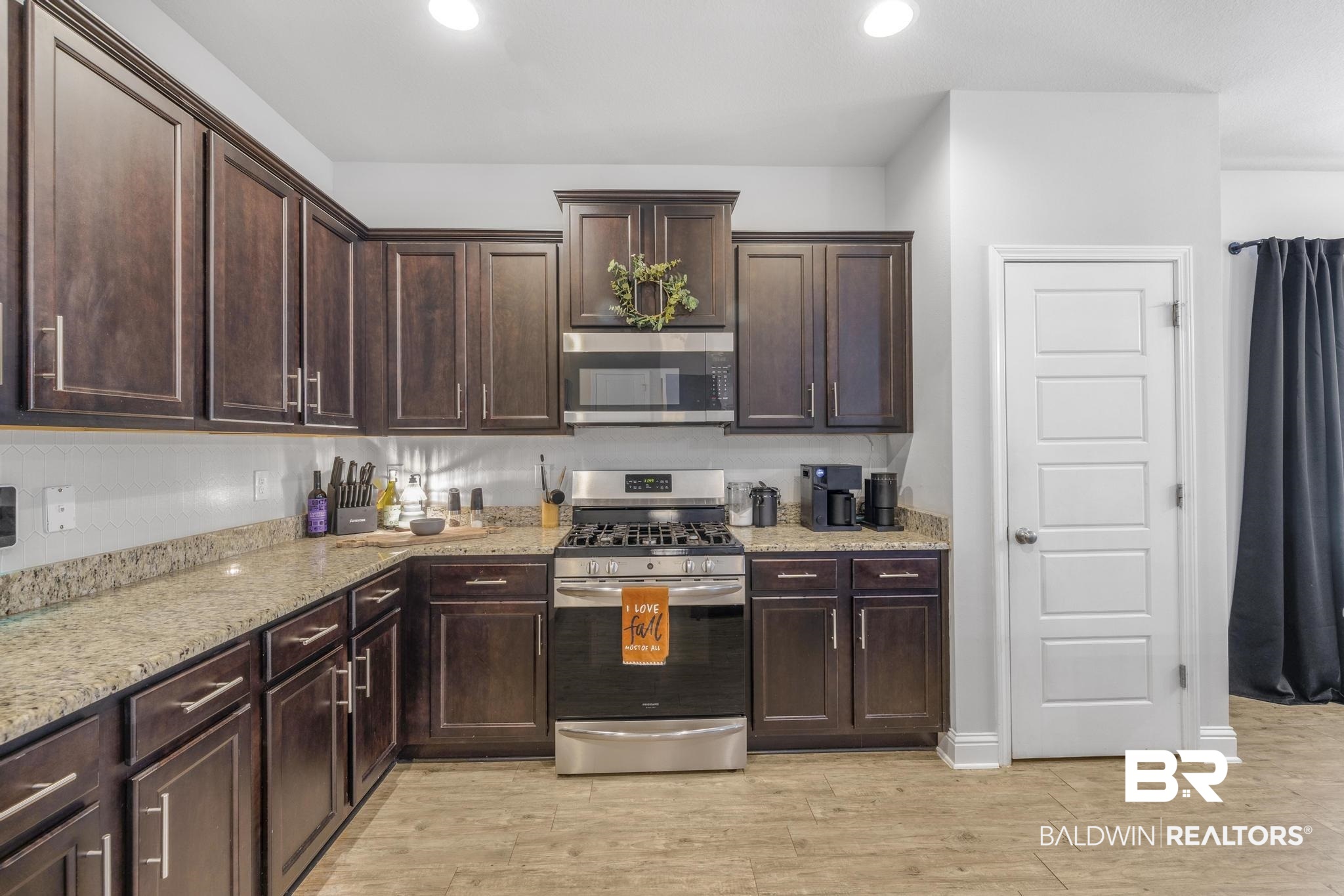 31336 Hoot Owl Road Daphne, AL 36527 - Photo 7 of 36 Kitchen featuring dark brown cabinetry, stainless steel appliances, light stone counters, recessed lighting, and light wood-type flooring
