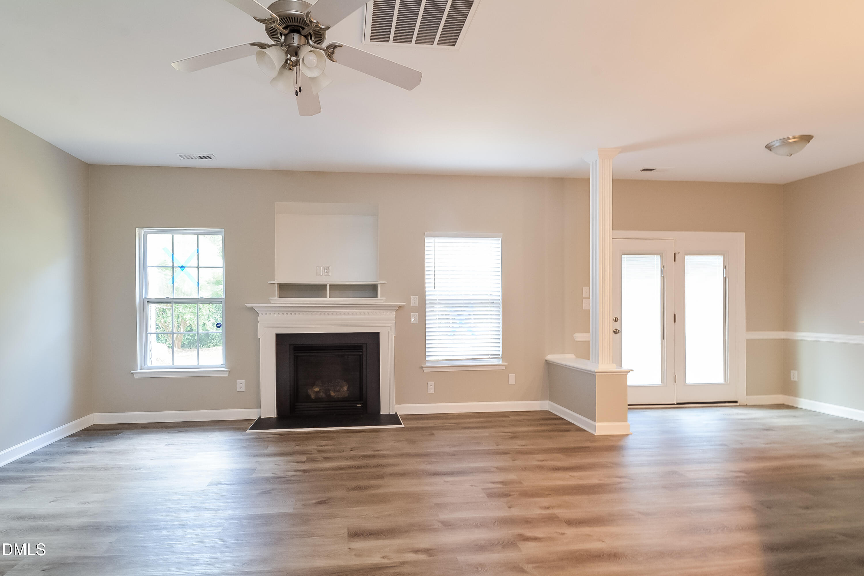2231 Lazy River Drive Raleigh, NC 27610 - Photo 2 of 17 an empty room with windows fireplace and wooden floor