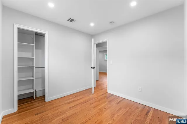 a view of an empty room with wooden floor and closet