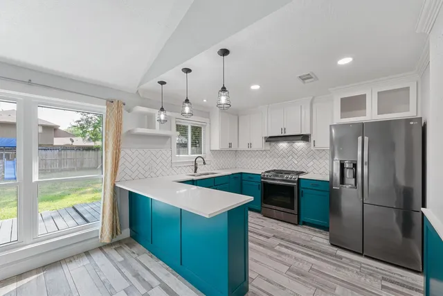 a kitchen with stainless steel appliances granite countertop a refrigerator a sink dishwasher a stove and white countertops with wooden floor