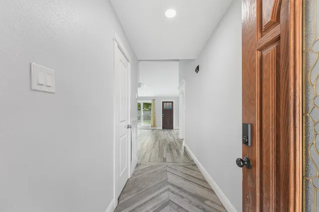 a view of a hallway with wooden floor and a bathroom
