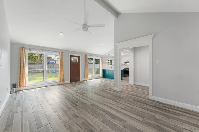 a view of an empty room with wooden floor and a window
