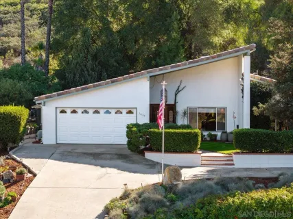 a view of a white house with a small yard and potted plants