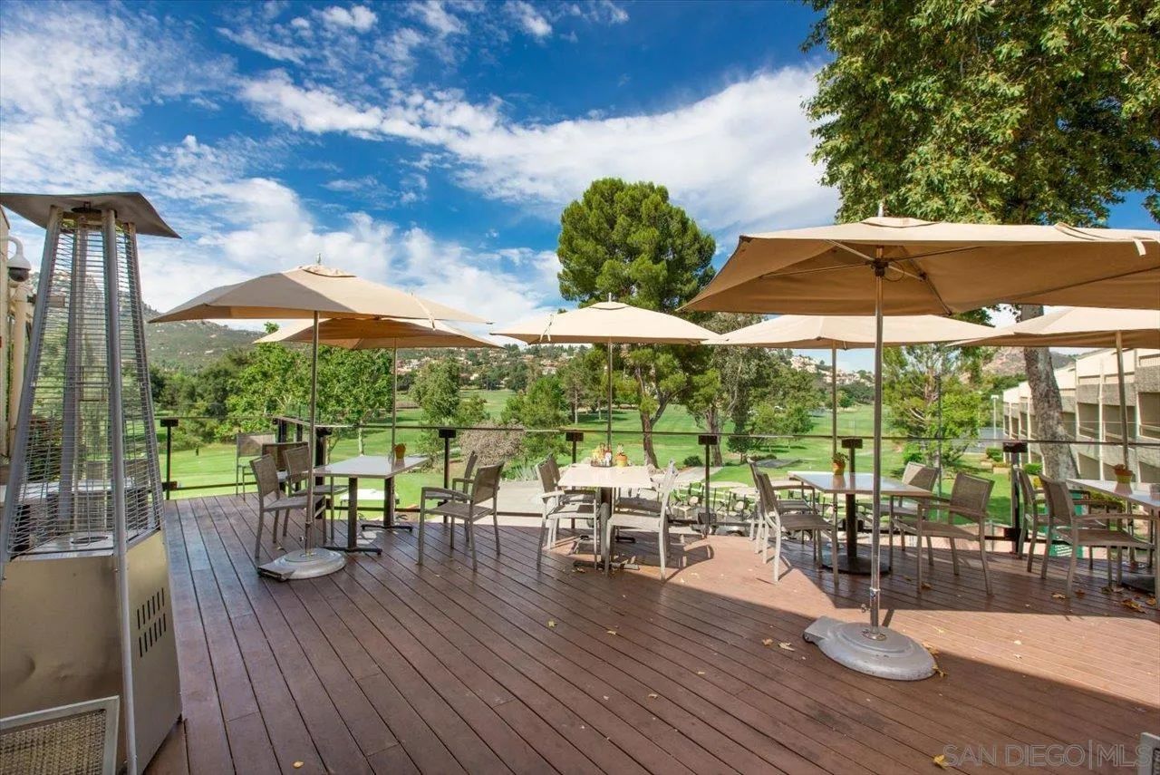 16109 Watt Way Ramona, CA 92065 - Photo 46 of 51 a view of a patio with dining table and chairs under an umbrella with wooden floor