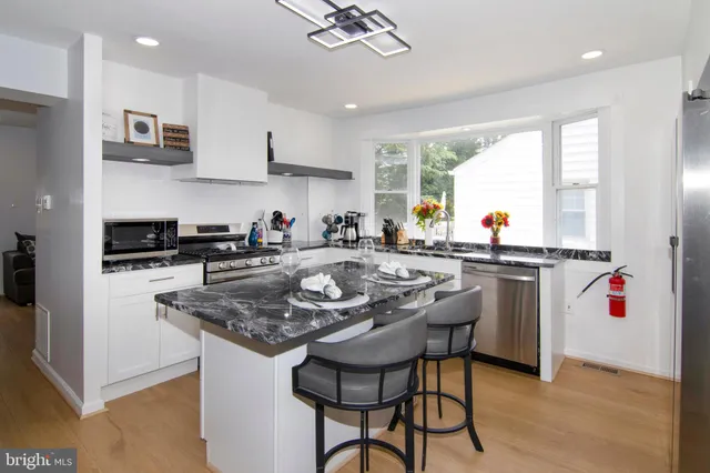 a kitchen with stainless steel appliances granite countertop a sink a stove a refrigerator and island with wooden floor