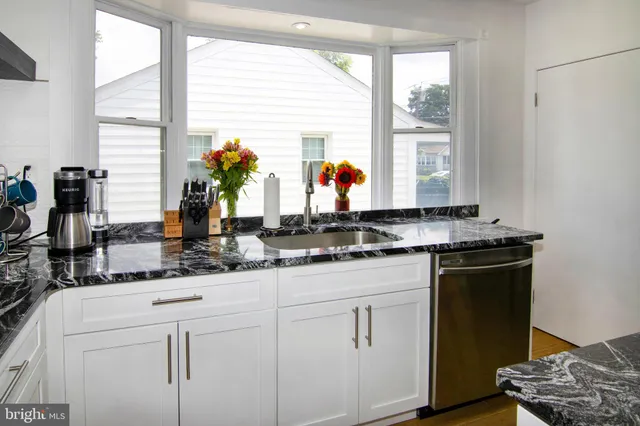 a kitchen with white cabinets and a large window