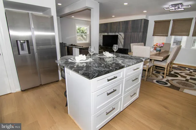 a kitchen with stainless steel appliances kitchen island granite countertop a table chairs and a refrigerator
