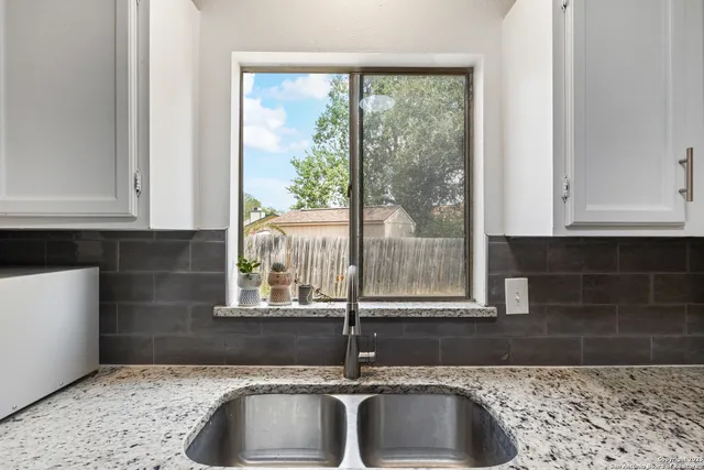 a kitchen with granite countertop white cabinets and a window