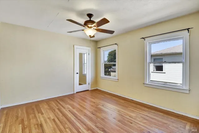 a view of an empty room with wooden floor and a window