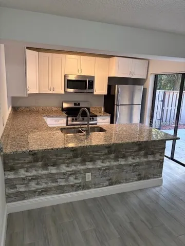 a view of a kitchen with kitchen island a sink wooden floor and a counter top space