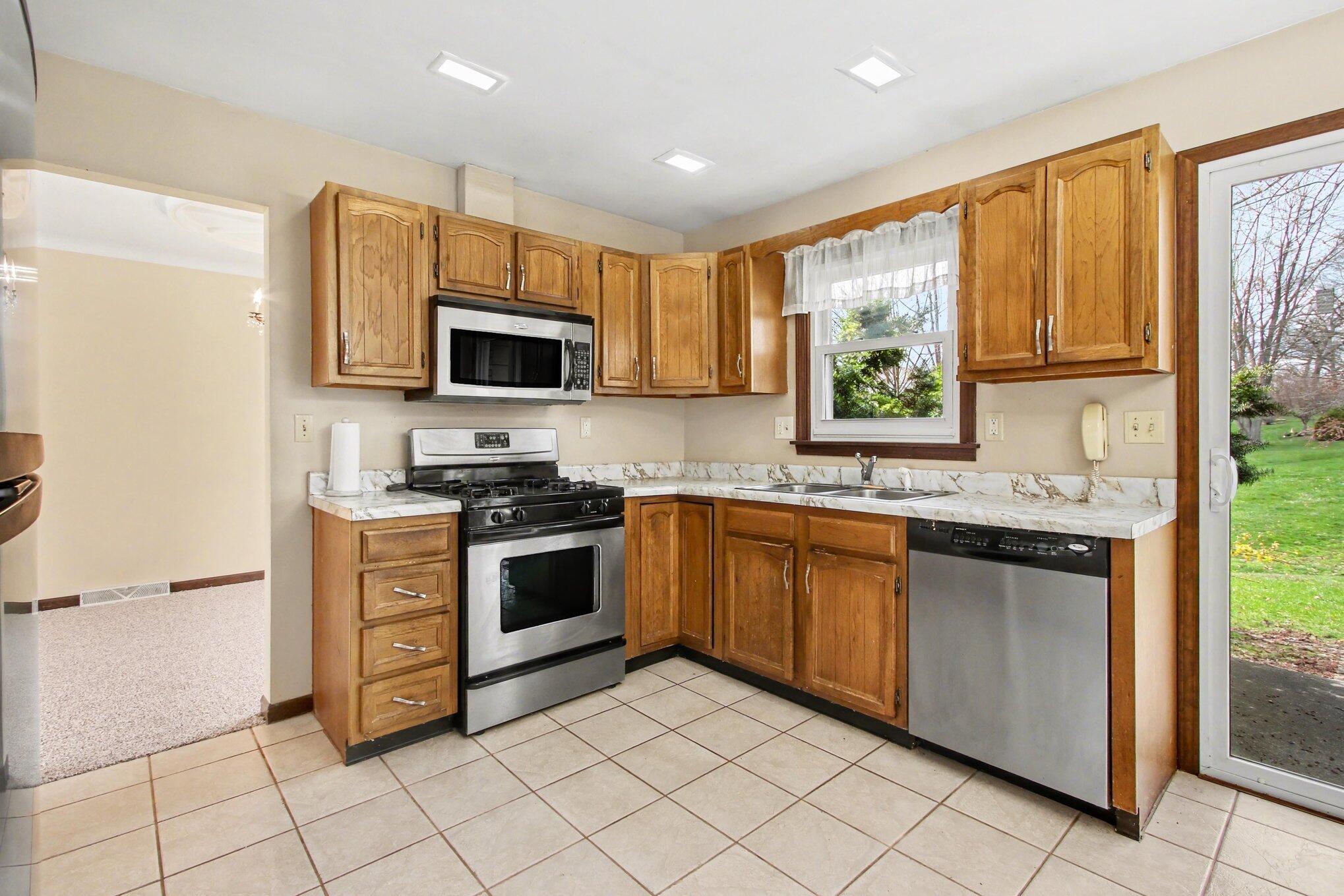 1379 Leeward Road Crown Point, IN 46307 - Photo 12 of 39 a kitchen with stainless steel appliances granite countertop a stove top oven a sink and a refrigerator