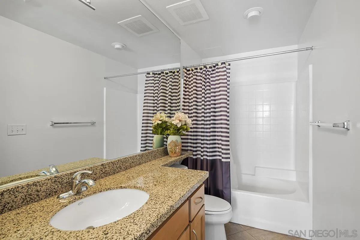 450 J Street, Unit 7071 San Diego, CA 92101 - Photo 18 of 33 a bathroom with a granite countertop sink a toilet a mirror and shower