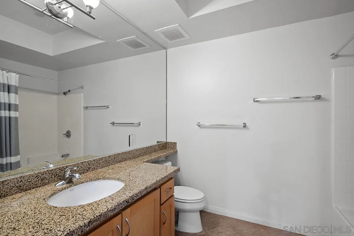 450 J Street, Unit 7071 San Diego, CA 92101 - Photo 19 of 33 a bathroom with a granite countertop sink a toilet and a mirror