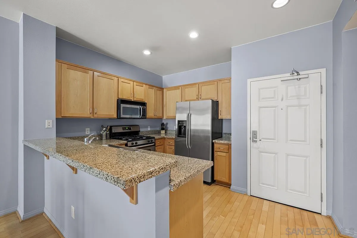 450 J Street, Unit 7071 San Diego, CA 92101 - Photo 10 of 33 a kitchen with granite countertop a refrigerator and a sink