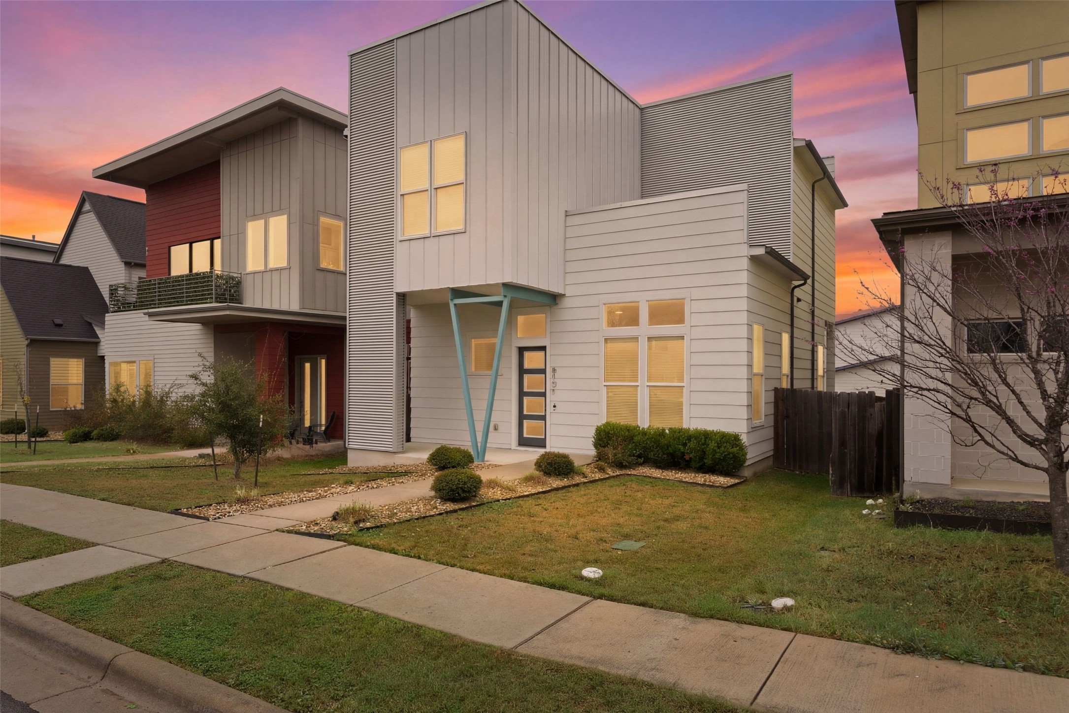Contemporary home with board and batten siding, a front lawn, and a balcony