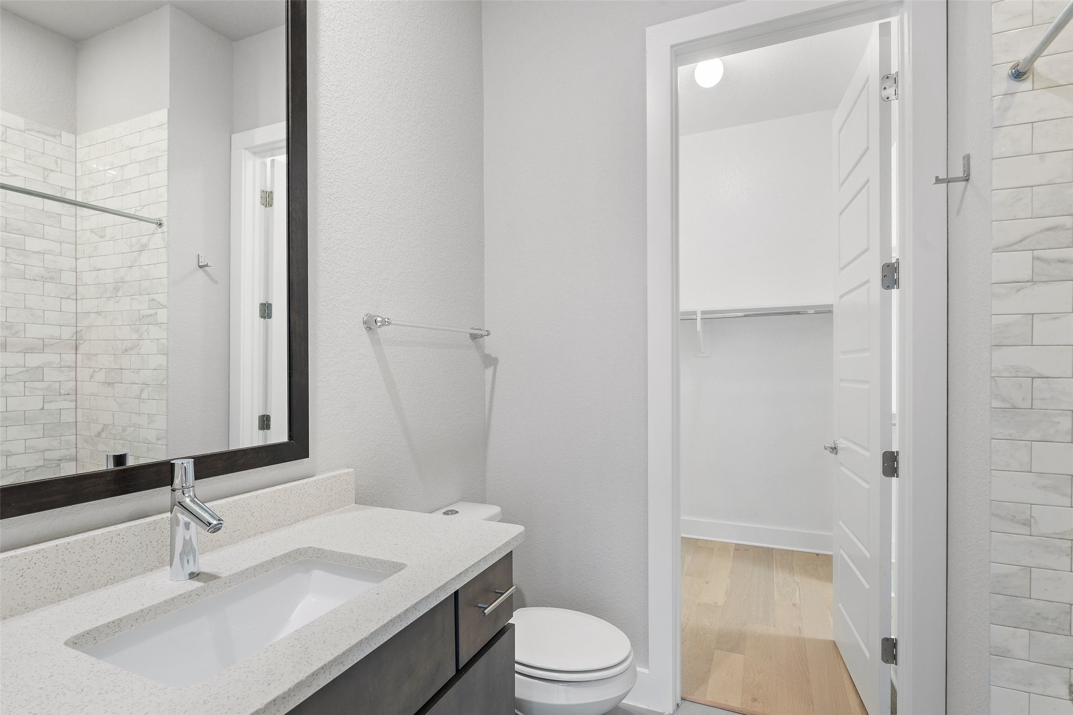 6104 Florencia Lane Austin, TX 78724 - Photo 16 of 31 Bathroom featuring tiled shower, vanity, a walk in closet, and light wood-style flooring