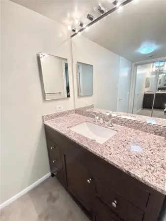 a bathroom with a granite countertop sink and a mirror