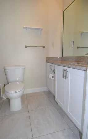 a bathroom with a granite countertop toilet and a sink