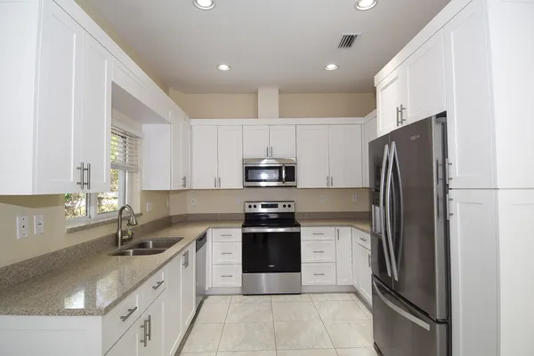 a kitchen with stainless steel appliances granite countertop a refrigerator and a sink