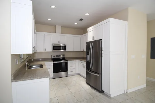 a kitchen with a refrigerator a stove top oven and cabinets