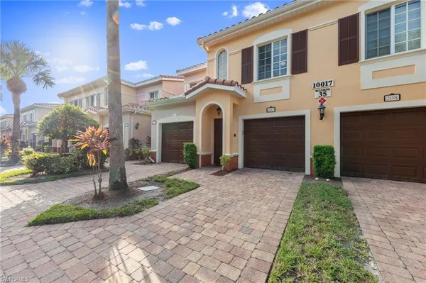a front view of a house with a yard and potted plants